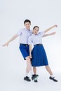 School children wearing school uniforms are dancing on white background. Asian girl and boy in students uniform on white