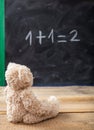 School class math. Teddy bear looking at a simple equation on a blackboard