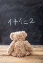 School class math. Teddy bear looking at a simple equation on a blackboard