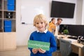 Boy holding green sign with word knowledgeable