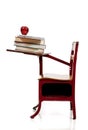 A school desk with books, computer and apple