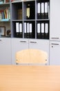School desk and chair positioned opposite a cabinet filled with organized folders, creating a minimalist study environment with Royalty Free Stock Photo