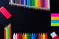 School and drawing supplies, on black background. Colored pencils, pencils, sticky note, eraser, sharpener and crayons. Royalty Free Stock Photo