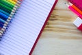 School and drawing supplies, on wooden table. Exercises book, colored pencils, eraser, pencil and ruler. Royalty Free Stock Photo