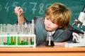 School education. Explore biological molecules. Toddler genius baby. Boy near microscope and test tubes in school