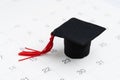 School, education or graduation ceremony schedule concept, small miniature graduation cap on white clean calendar