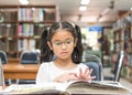 School education and literacy concept with Asian kid student learning and reading book in library or classroom Royalty Free Stock Photo