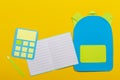 School education papercut background. School bag backpack, notebooks and calculator paper cut on yellow background