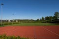 School empty soccer field near a forest in the hills. Daytime, blue sky, trees in the background, flood lights, no people Royalty Free Stock Photo