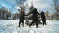 School friends run around the spruce tree holding hands. Christmas concept.