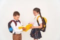 Schoolgirl and schoolboy with backpacks look at a book on a white background Royalty Free Stock Photo