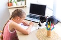 School girl doing homework at home, writing or drawing, cat lying nearby. Royalty Free Stock Photo