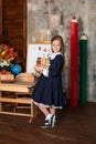 School Girl in dress holds a stack of books. Back to school. Happy smiling Little girl with books stand near of chalkboard. Royalty Free Stock Photo