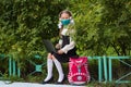 School girl in a medical mask, headphones engaged in a park on a laptop. Back to school. Virus protection for schools.