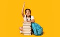 School Girl Raising Hand Sitting At Book Stack, Studio Shot Royalty Free Stock Photo