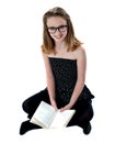 School girl sitting on floor holding book Royalty Free Stock Photo