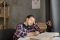 school girl is sleeping on open book while doing homework at home, tired from studying, exhausted. Distance learning Royalty Free Stock Photo