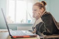 School girl studying homework using a laptop and headphones during online lesson at home, social distance during quarantine, self-