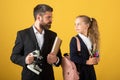 School girl with teacher in school. Studio portrait of tutor and young school girl with backpack and textbook.