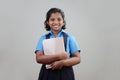 A school girl wearing uniform holds note books in hand Royalty Free Stock Photo