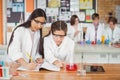 School girls writing in journal book while experimenting in laboratory at school