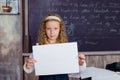 School is a happy place. Happy small child holding blank paper on blackboard background. Little girl happy smiling with Royalty Free Stock Photo