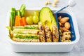 School healthy lunch box with sandwich, cookies, fruits and avocado on white background Royalty Free Stock Photo