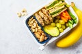 School healthy lunch box with sandwich, cookies, fruits and avocado on white background Royalty Free Stock Photo