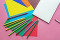 School and hobby concepts. Colored paper sheets, colored pencils and open sketchbook Royalty Free Stock Photo