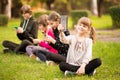 School holidays. Happy child girl take selfie on phone with group of happy friends outdoors in park Royalty Free Stock Photo