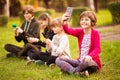 School holidays. Happy child girl take selfie on phone with group of happy friends outdoors in park Royalty Free Stock Photo