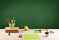 School items on desk with empty chalkboard Royalty Free Stock Photo