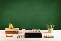 School items on desk with empty chalkboard Royalty Free Stock Photo