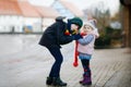 School kid boy and brother warming hands of little sister, toddler girl on cold snowy grey winter day. Family, two Royalty Free Stock Photo