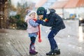 School kid boy and brother warming hands of little sister, toddler girl on cold snowy grey winter day. Family, two Royalty Free Stock Photo