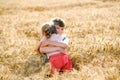 School kid boy and little sister, preschool girl hugging on wheat field. Two happy children playing together and having Royalty Free Stock Photo