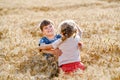 School kid boy and little sister, preschool girl hugging on wheat field. Two happy children playing together and having Royalty Free Stock Photo