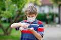 School kid boy with medical mask as protection against pandemic coronavirus quarantine disease. Child holding bottle Royalty Free Stock Photo