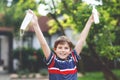 School kid boy with medical mask as protection against pandemic coronavirus quarantine disease. Child holding bottle Royalty Free Stock Photo