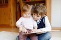 School kid boy reading book for little toddler baby girl, Two siblings sitting together and read books. Beautiful lovely Royalty Free Stock Photo