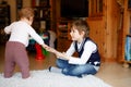 School kid boy reading book for little toddler baby girl, Two siblings sitting together and read books. Beautiful lovely Royalty Free Stock Photo