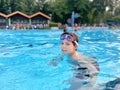 School kid boy splashing in an outdoor swimming pool on warm summer day. Happy healthy preteen child enjoying sunny