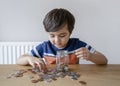 School Kid putting money coins into clear jar, Child counting his saving money, Young boy holding coin on his hands, Children