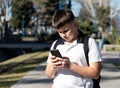 School kid using his mobile in the middle of the street on a sunny day Royalty Free Stock Photo