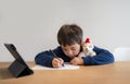 School Kid using pen drawing cartoon on paper, Child sitting alone doing home work, Young boy using digital pad searching Royalty Free Stock Photo