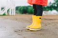 School kid wearing yellow gumboots at the beach. Child standing in the sand in waterproof rubber boots