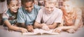 School kids reading book together in library