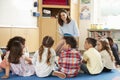 School kids sitting on floor in front of teacher, low angle