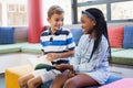 School kids sitting together on sofa and reading a book Royalty Free Stock Photo