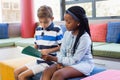 School kids sitting together on sofa and reading a book Royalty Free Stock Photo